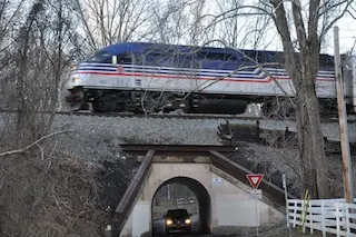 A Virginia Railway Express train crossing the Colchester Overpass, known as Bunny Man Bridge, as a vehicle passes underneath.
