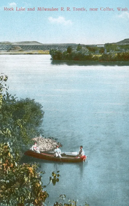 A circa 1910 postcard of women boating on Rock Lake, Washington, with the Milwaukee Railroad trestle behind them.