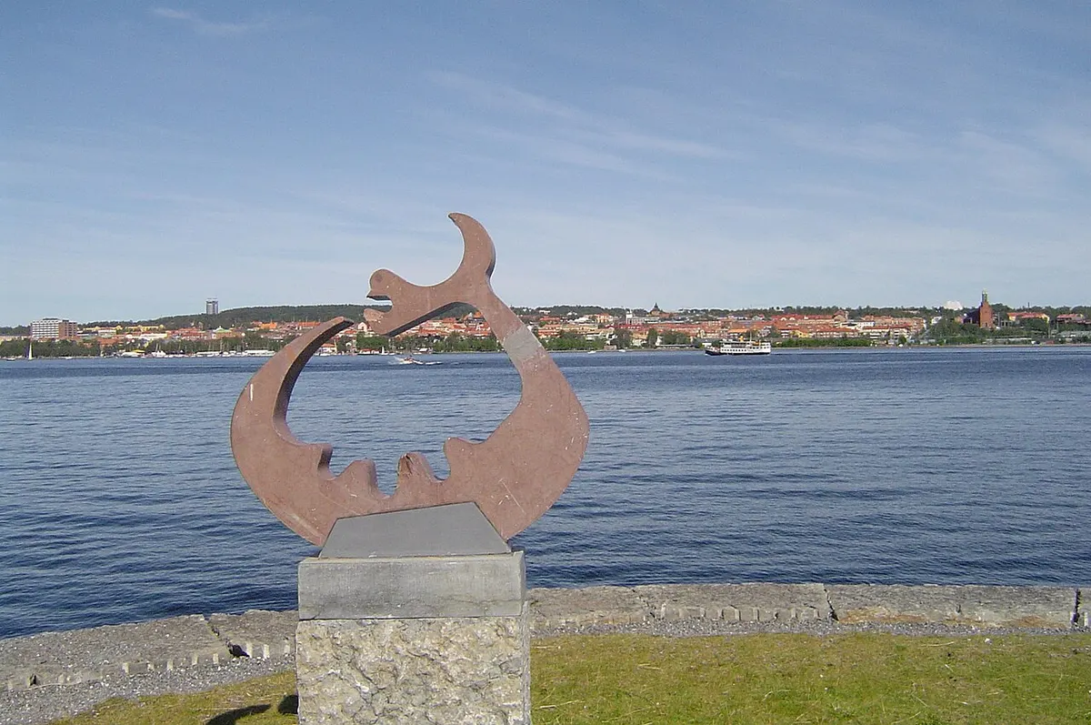A dragon-like sculpture of the Storsjö monster on the shore of Lake Storsjön, with the city of Östersund in the background.