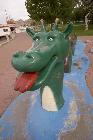 Green fibreglass Ogopogo statue with humped coils on the Kelowna waterfront