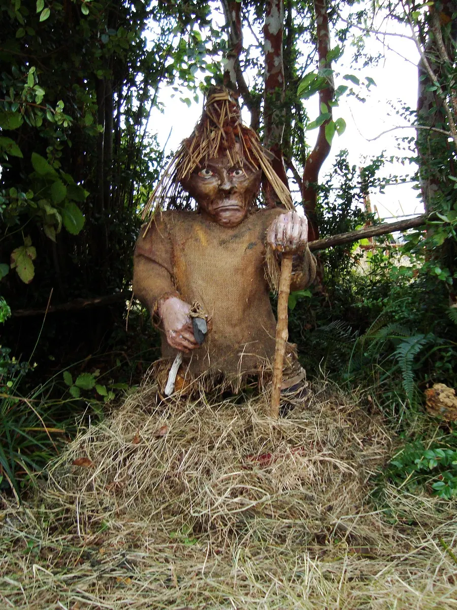 A carved and painted statue of the Trauco, a small bearded man with a hat and axe, in the municipal park of Castro, Chiloé.