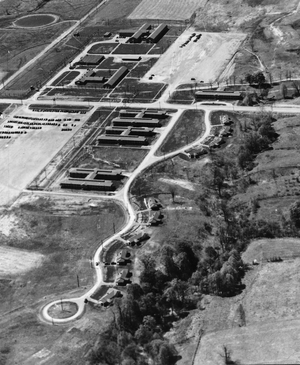 Black-and-white aerial photograph of rows of wartime staff houses and dormitory buildings among fields