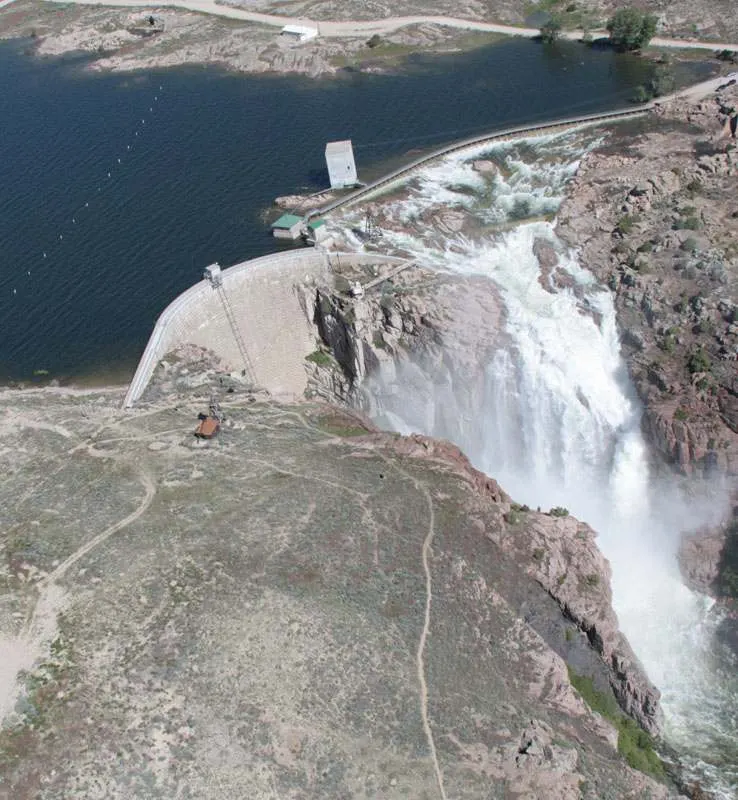 Aerial view of water pouring over the spillway of Pathfinder Dam into a rocky granite canyon